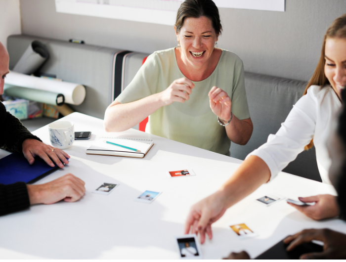 Group of four people playing a card game and smiling