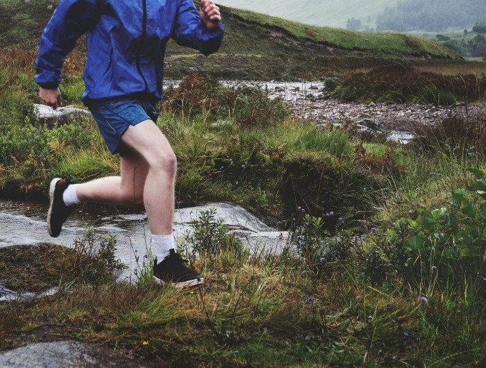 Young man running along uneven ground in trainers