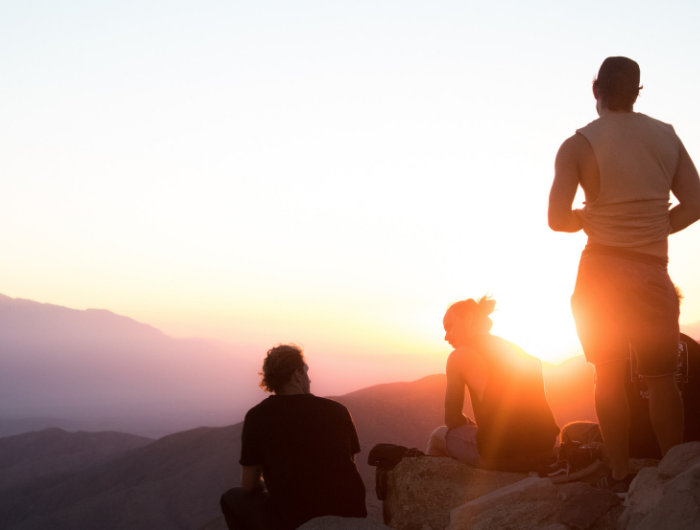 Three young people looking at a sunset on a mountain