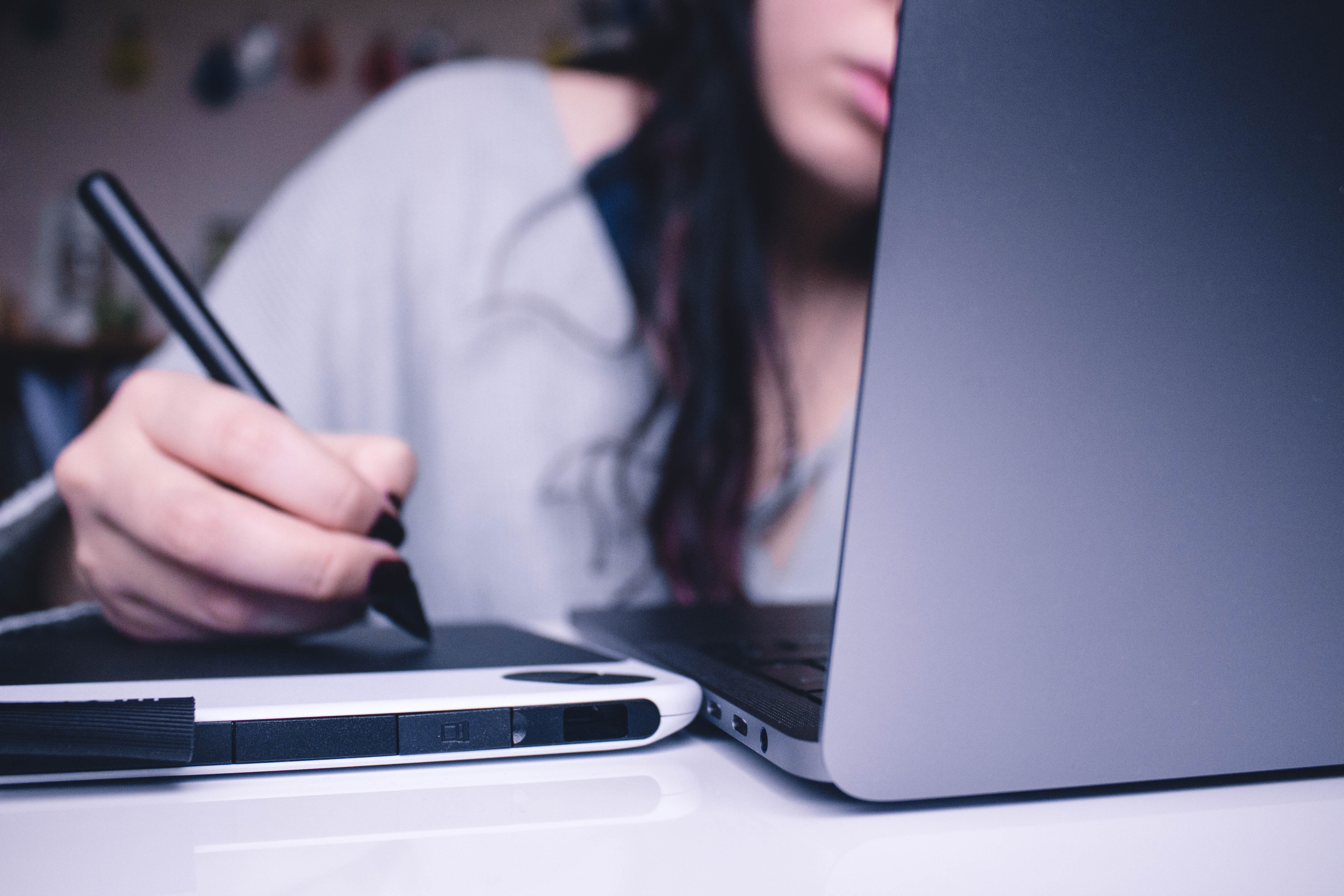 Girl holding pen working with laptop