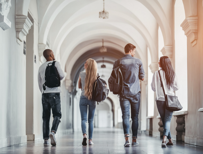 Group of University students walking down hallway chatting