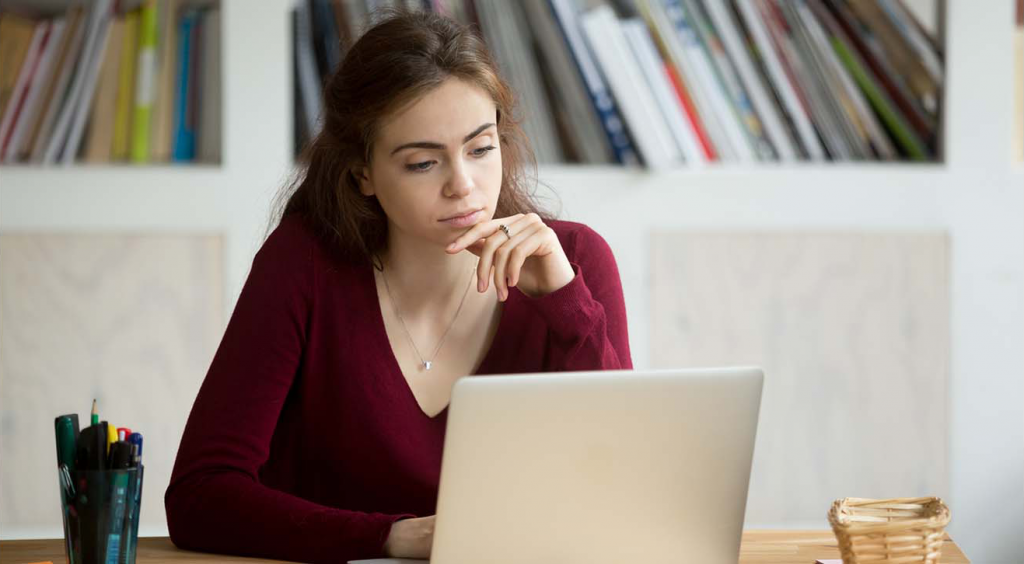 Young woman sat at computer thinking