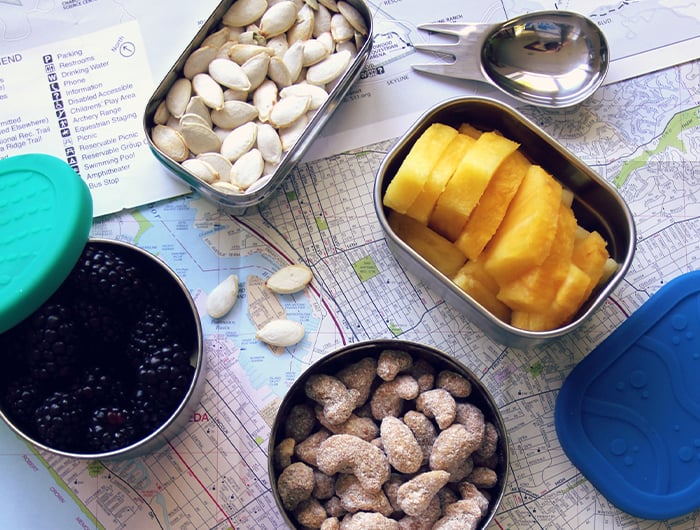 Metal tins of nuts and fruit resting on map.