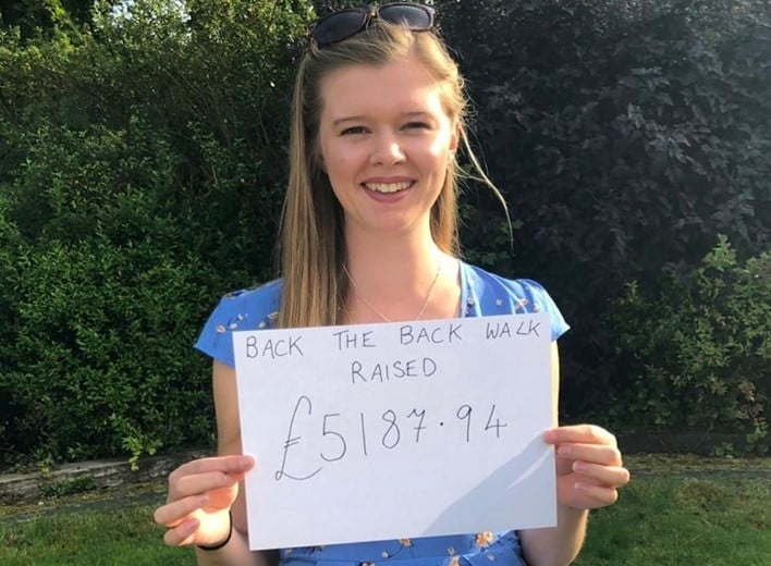 Young woman holding white sign raising £5187.94 for charity