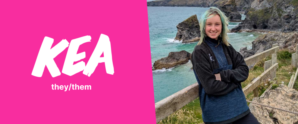A split design image. On the left, a bright pink background features the name 'KEA' in large, white, bold brushstroke-style letters, with 'they/them' written underneath in smaller text. On the right, a person with light skin and blonde hair with blue highlights is smiling at the camera while leaning against a wooden fence. They are wearing a navy blue and black fleece jacket. The background showcases a coastal landscape with rocky cliffs and turquoise ocean waves crashing against the shore.