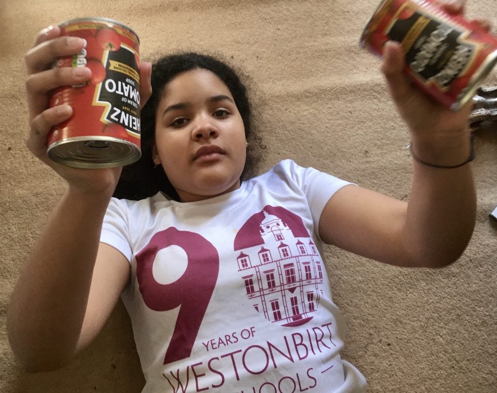 Young girl laying on floor holding two cans