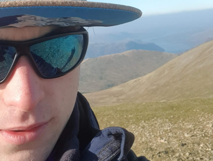 Guy hiking with sunglasses and a hat on