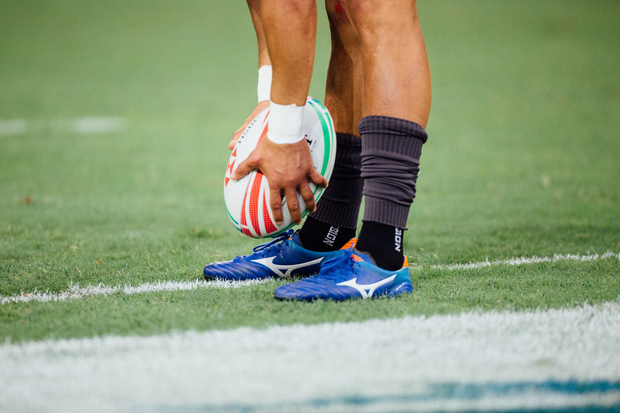 Man wearing boots holding rugby ball