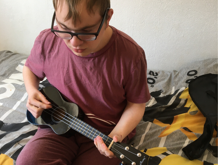 Young man playing ukulele in bedroom