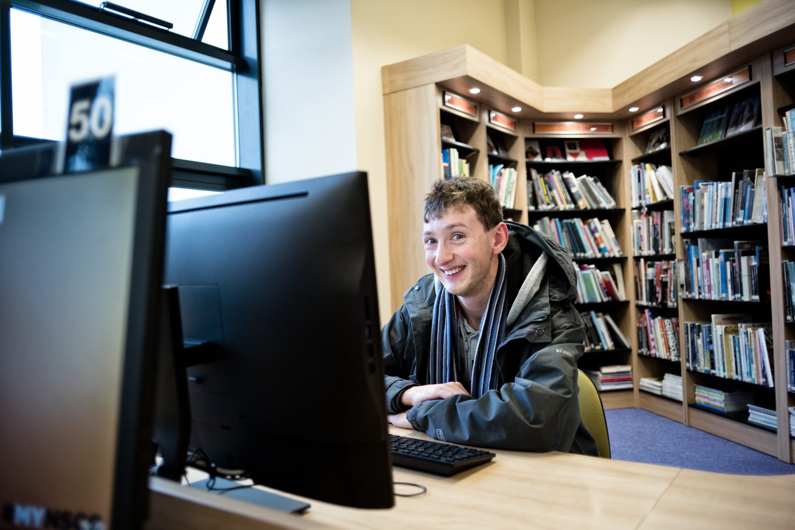 Young man siting at computer in library