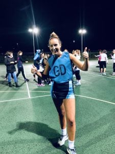 Girl with blond hair in netball uniform 