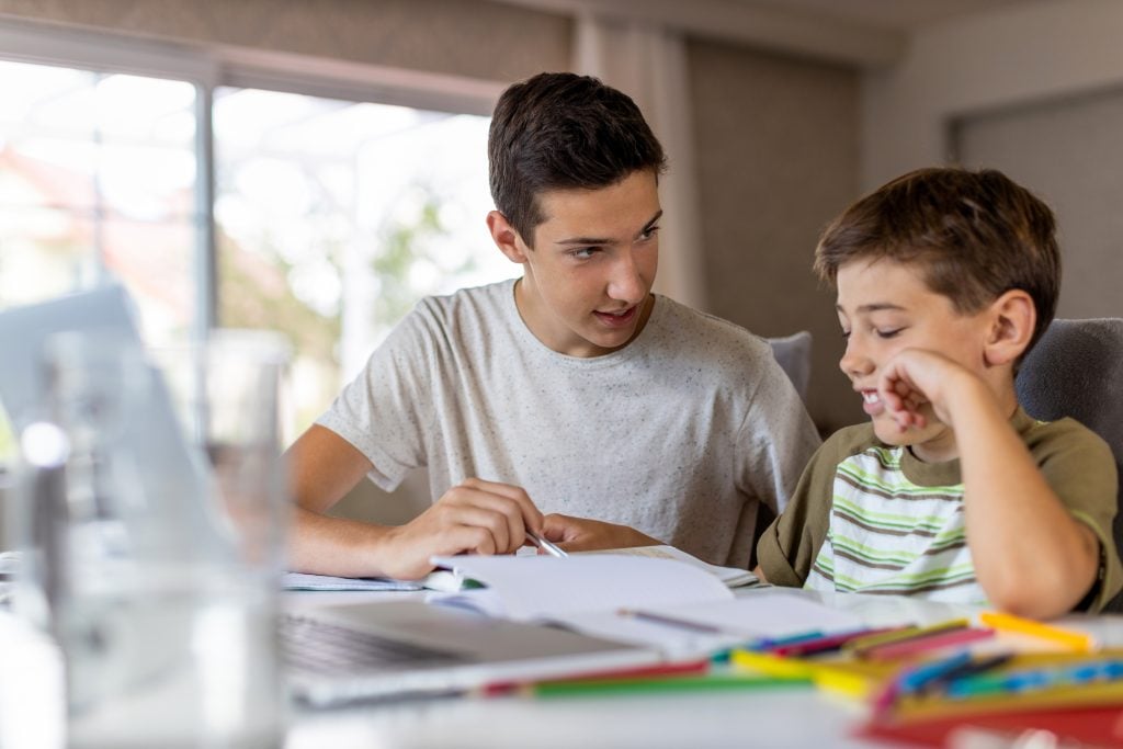 Teenager helping young child with homework