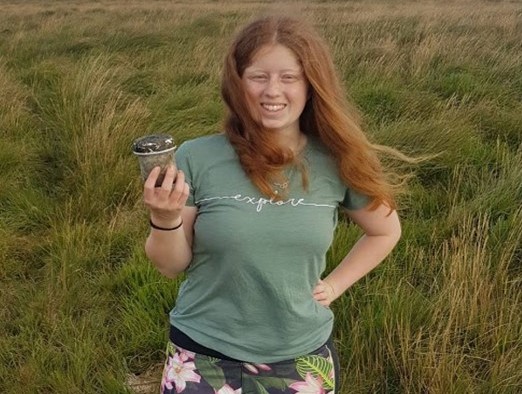 Freya a young woman standing in a field wearing a green t shirt