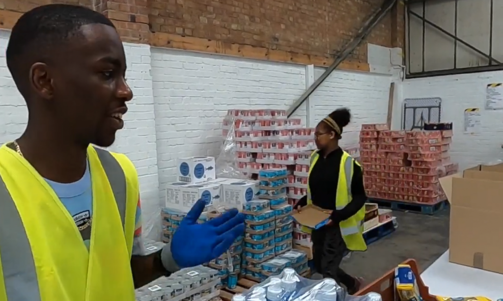 Two young people in high vis jackets working at a food bank