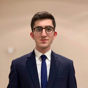 Young man in blue suit and tie wearing glasses