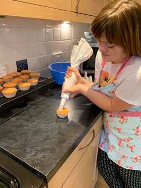 Young woman icing a cupcake in kitchen