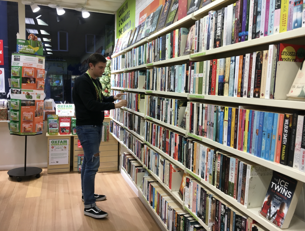 Lee looking at books on shelf in library