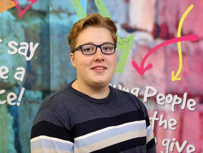 Headshot of James in blue jumper wearing glasses