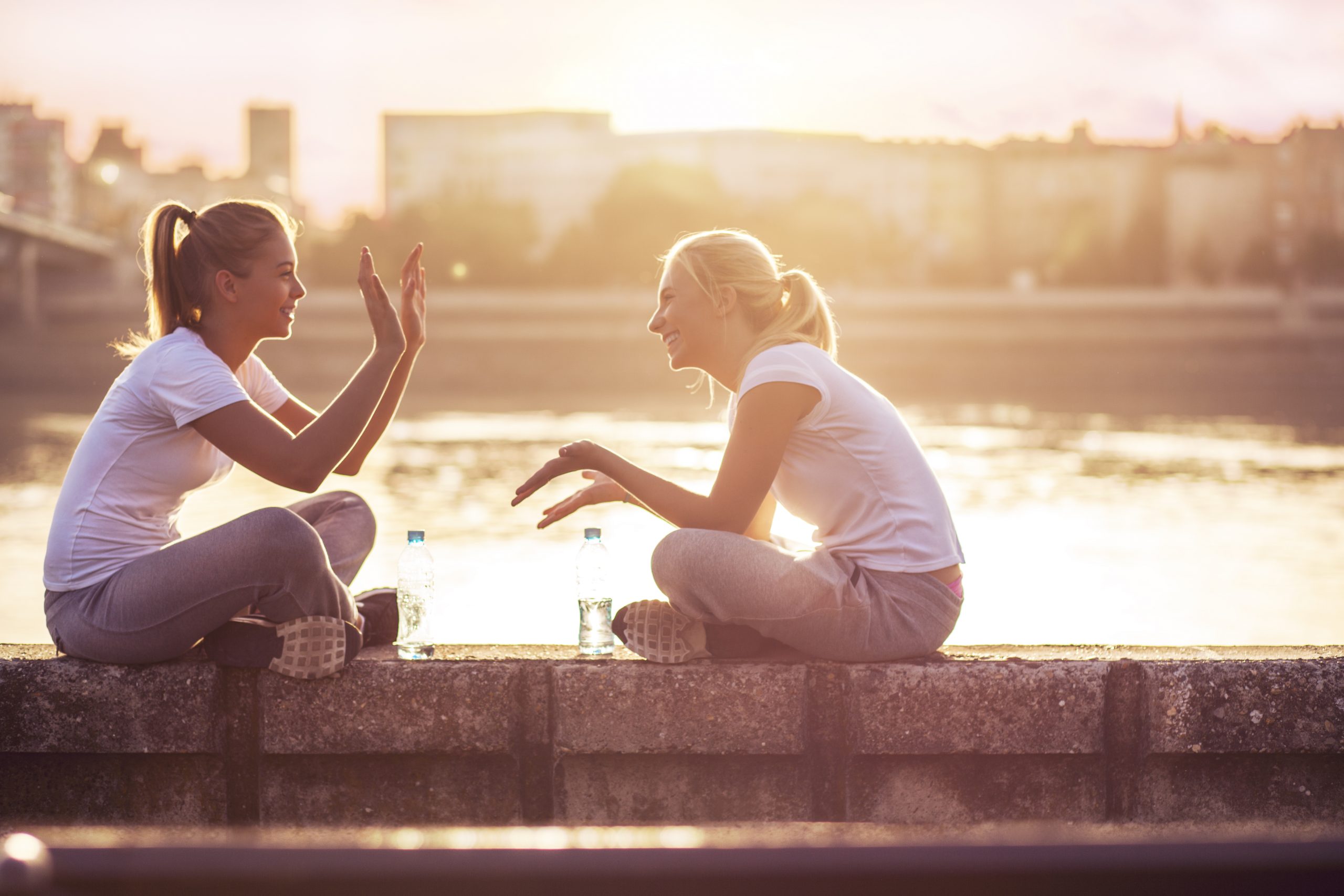 2 young women talking to each other on brick wall