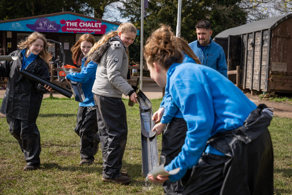 Young people working together to move water down sections of pipes.