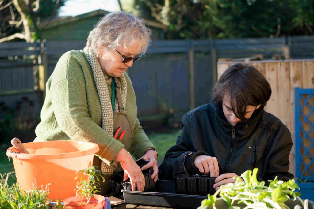 A volunteer and a D of E Participant planting seeds together.