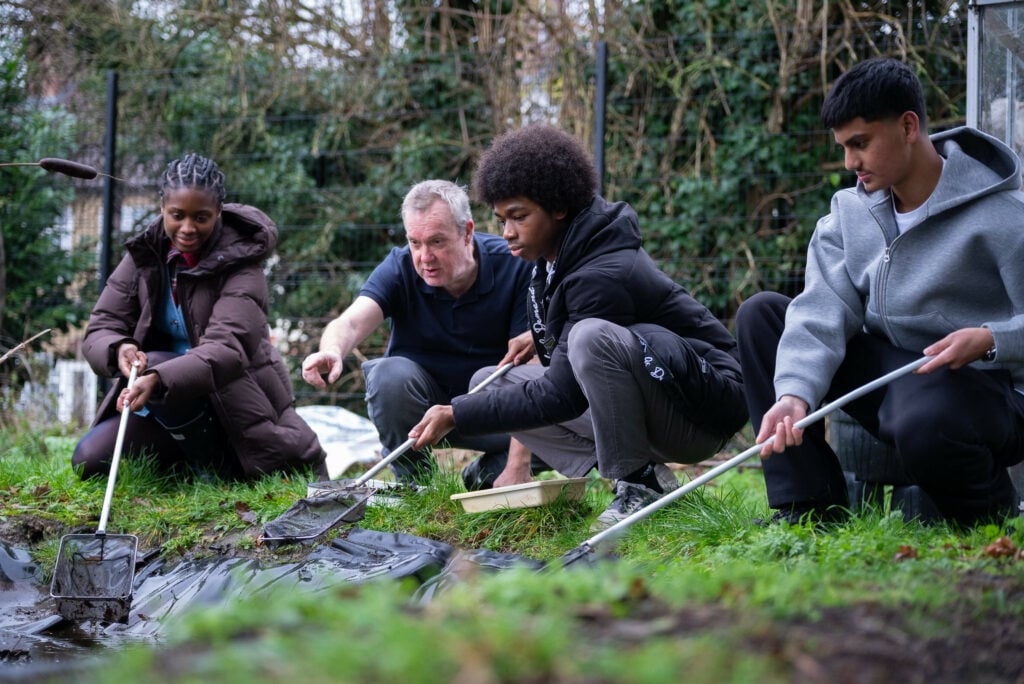 A group of three young people and one adult volunteer doing a forest clear up.