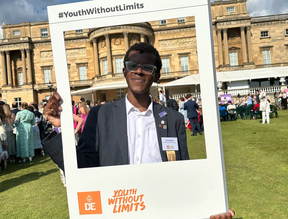 Christopher holding a Youth Without Limits frame in front of Buckingham Palace.