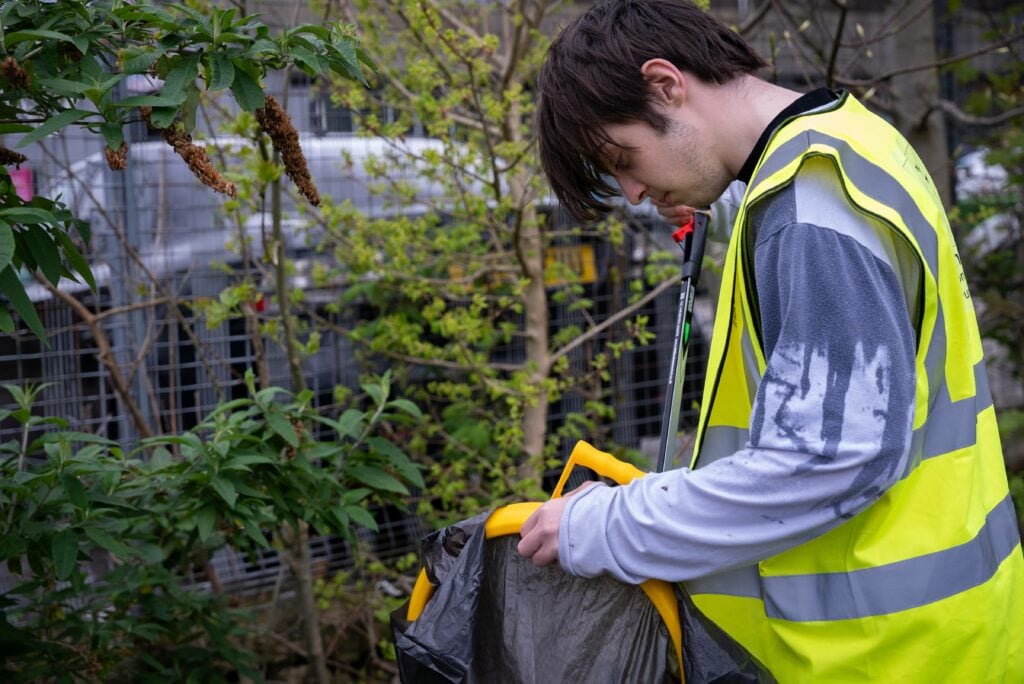 Lewis wearing a high-vis vest doing litter picking in his community.