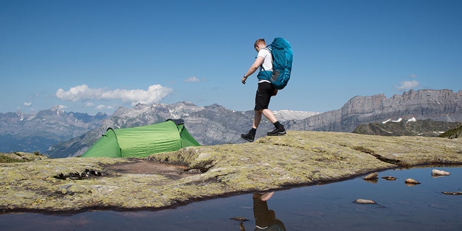 Young person waling to a tent in the hills