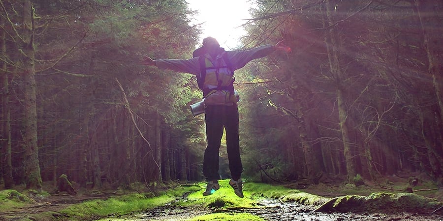 Young person jumping with sun shining behind