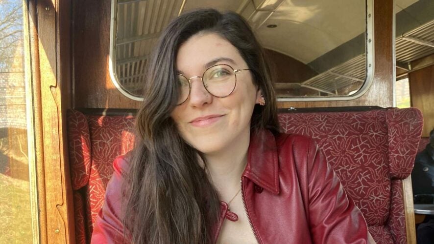 Charlotte has brown hair, glasses and a red jacket.