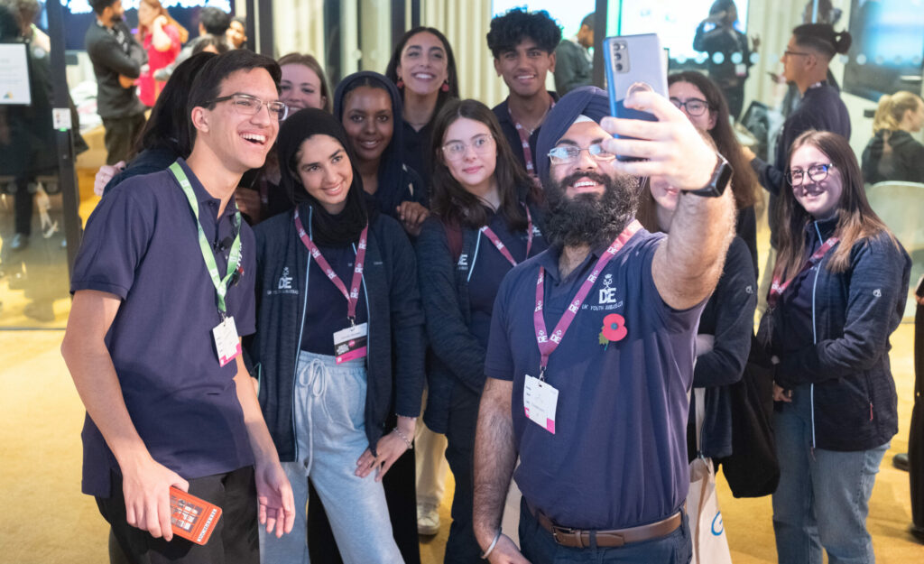 Baljodh taking a selfie with a group of D of E youth ambassadors wearing blue polo shirts.