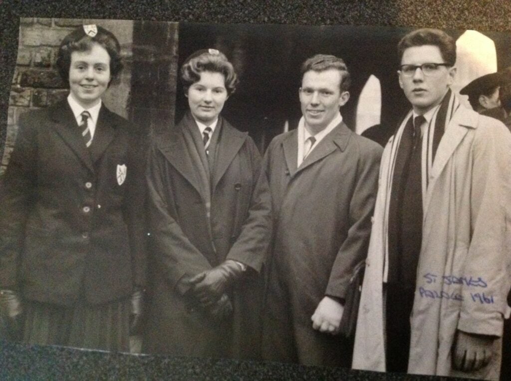 A black and white photo of four young people dressed in smart clothing. There are two women on the left hand side, and two men on the right hand side. There is a small annotation in the bottom right, which says "St James Palace 1961".