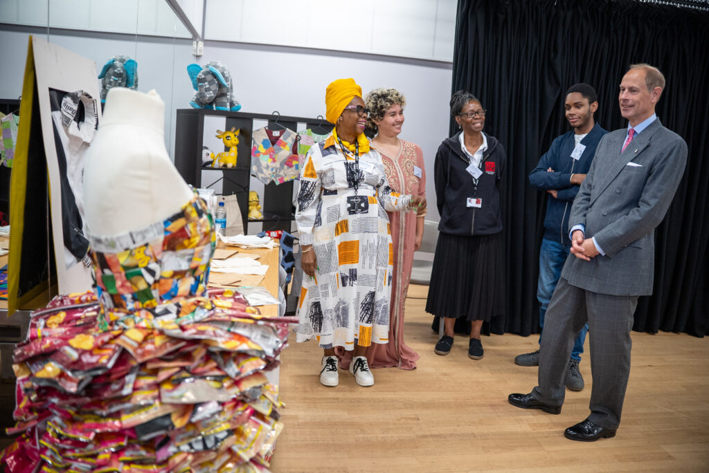 HRH The Duke of Edinburgh listens as participants present a creative arts display featuring textiles, artwork and recycled materials.
