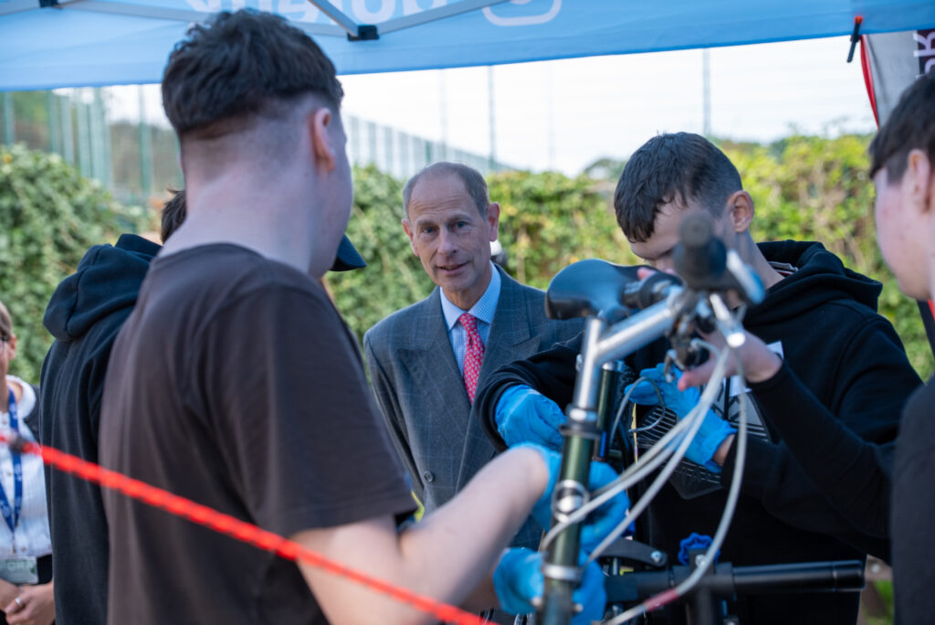 HRH The Duke of Edinburgh speaks with participants as they carry out bicycle maintenance during a DofE activity.