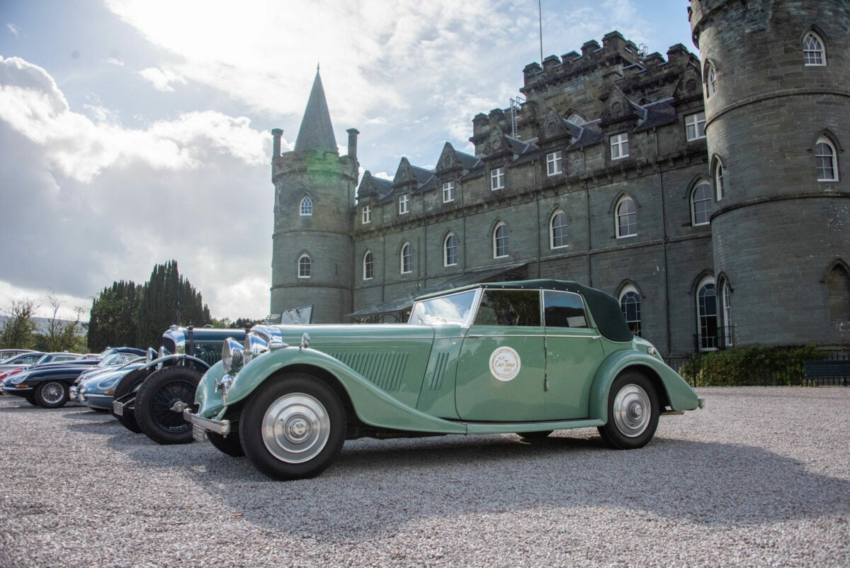 Vintage green car in front of stately home