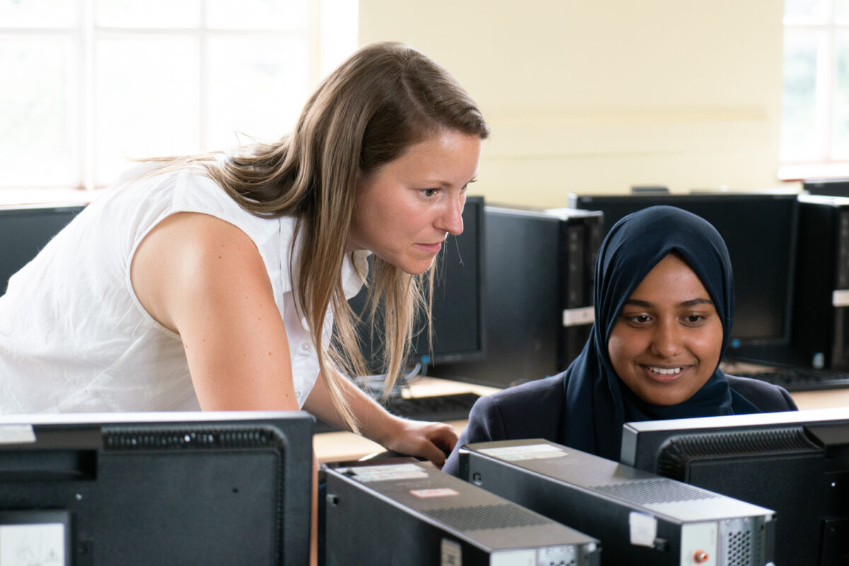 A young person and a D of E leader looking at a computer screen together.