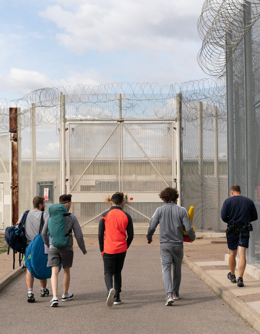 4 young offenders and a prison officer walking towards some gates.