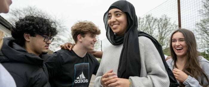 Four young people laughing together outside.