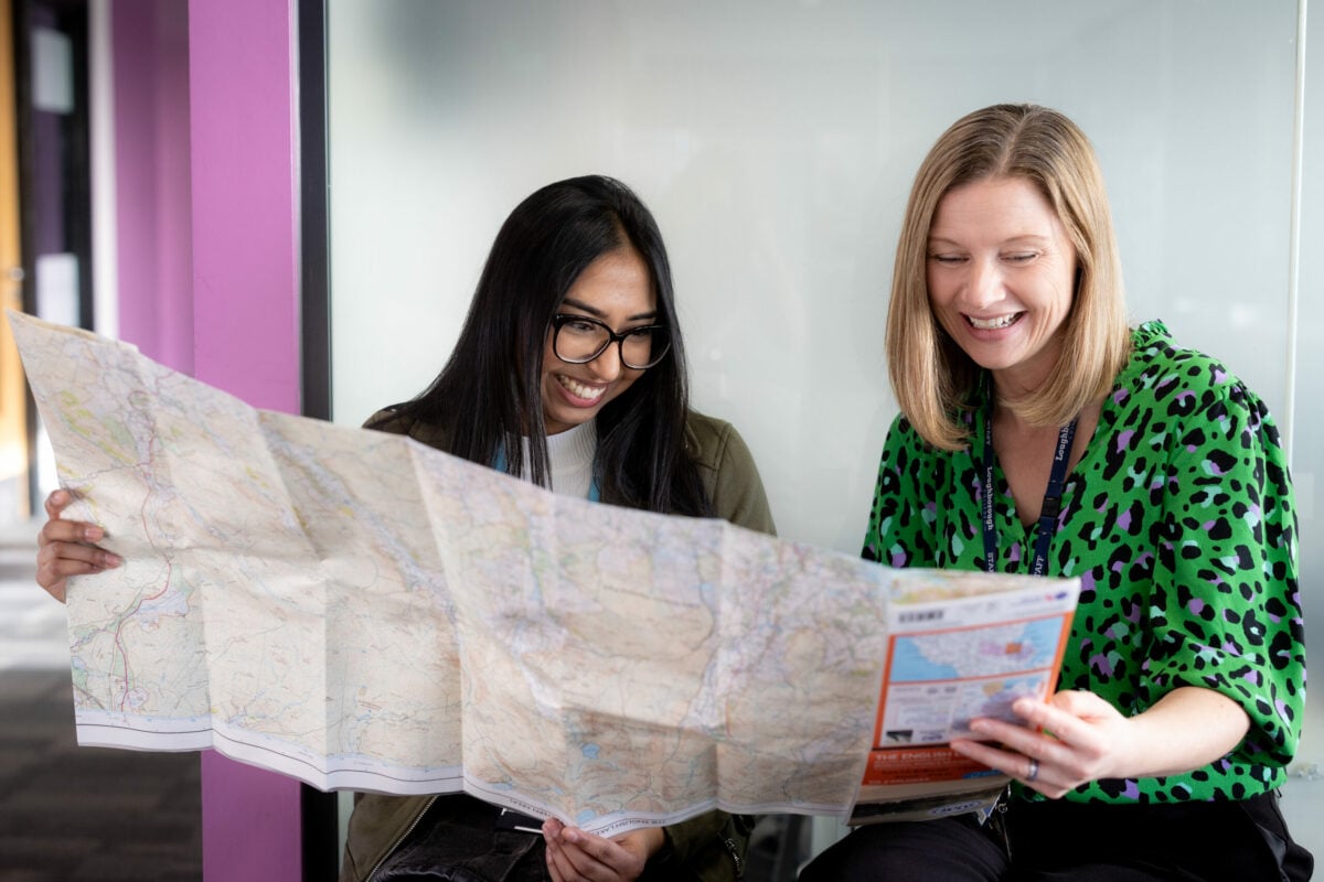 Two people holding and looking at a large map.