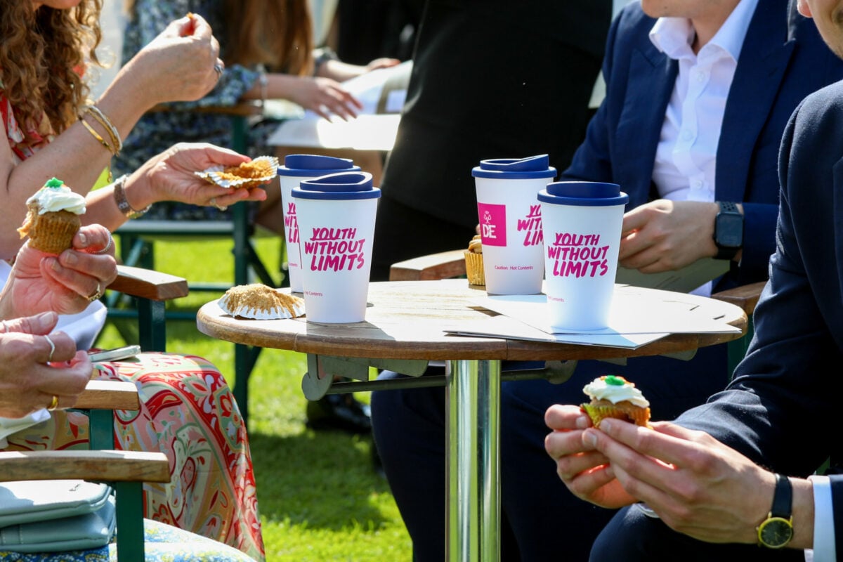 A close-up of a wooden outdoor table with several reusable cups that have 