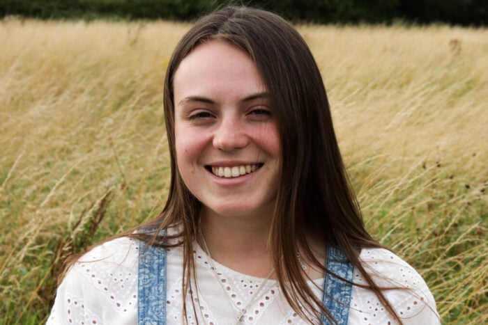 Amy standing in a grassy field, smiling