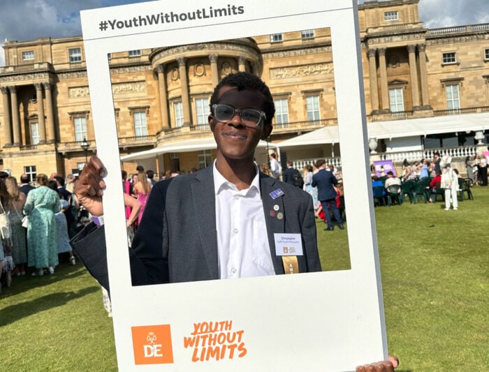 Christopher holding a Youth Without Limits frame in front of Buckingham Palace.