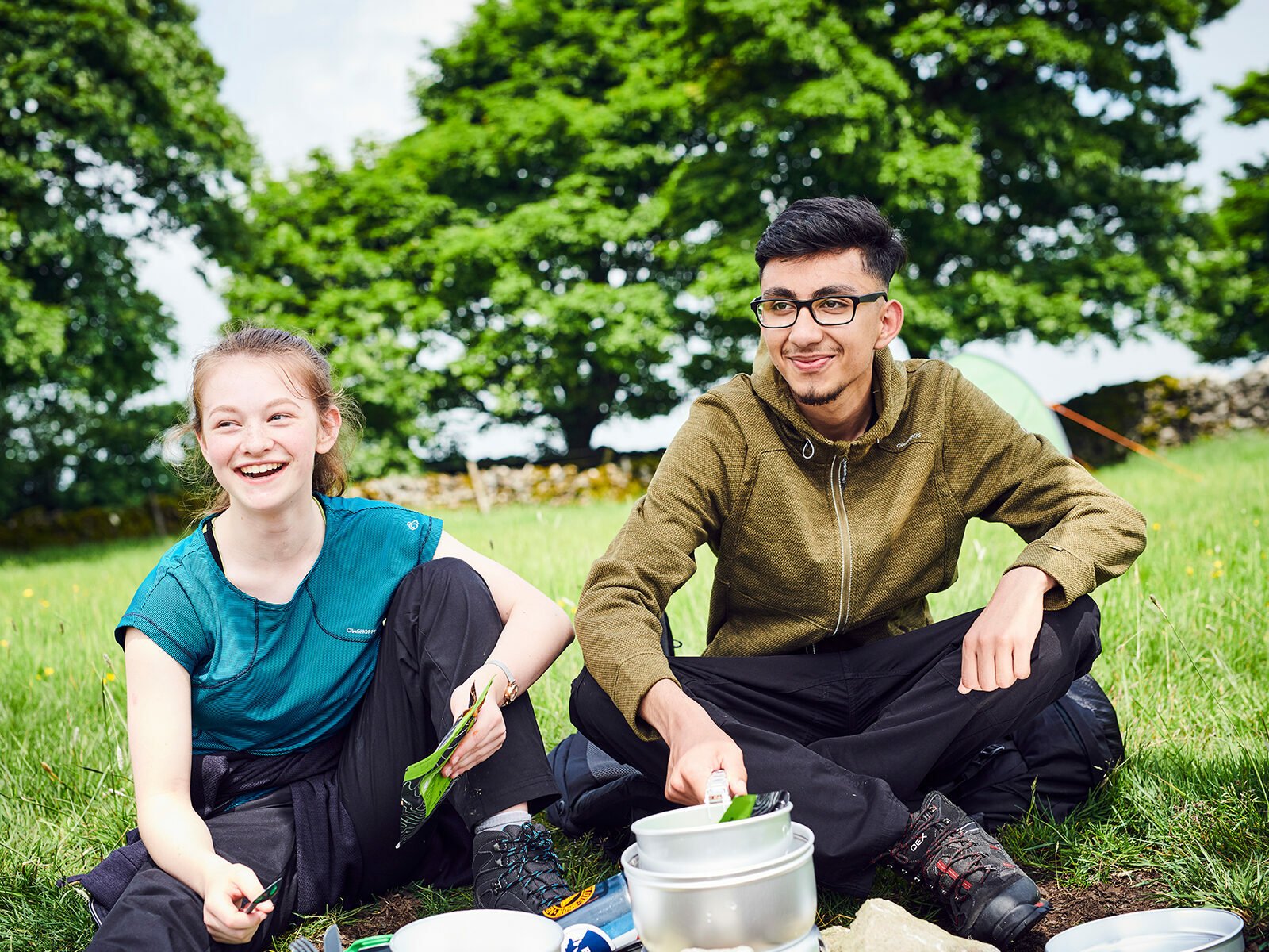 Two young people smiling and using a stove