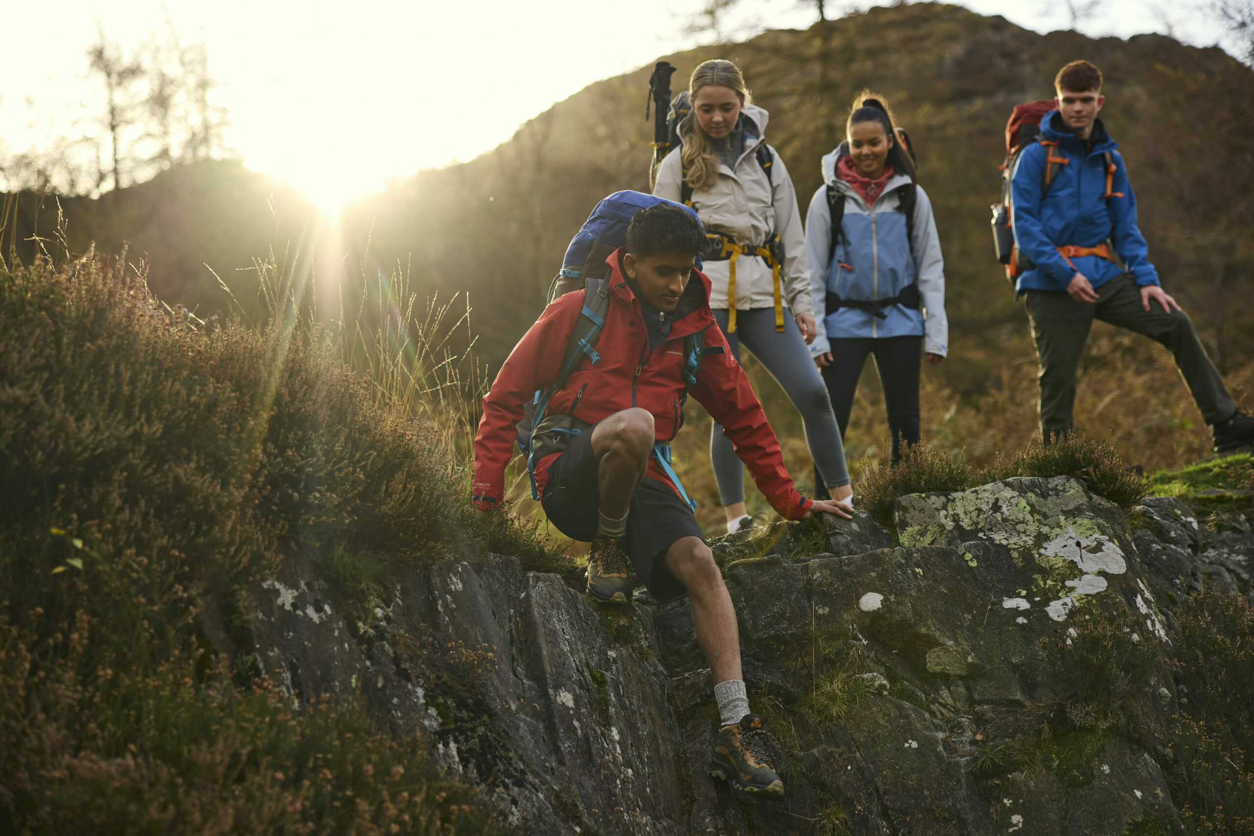 Young people climbing down a rock edge