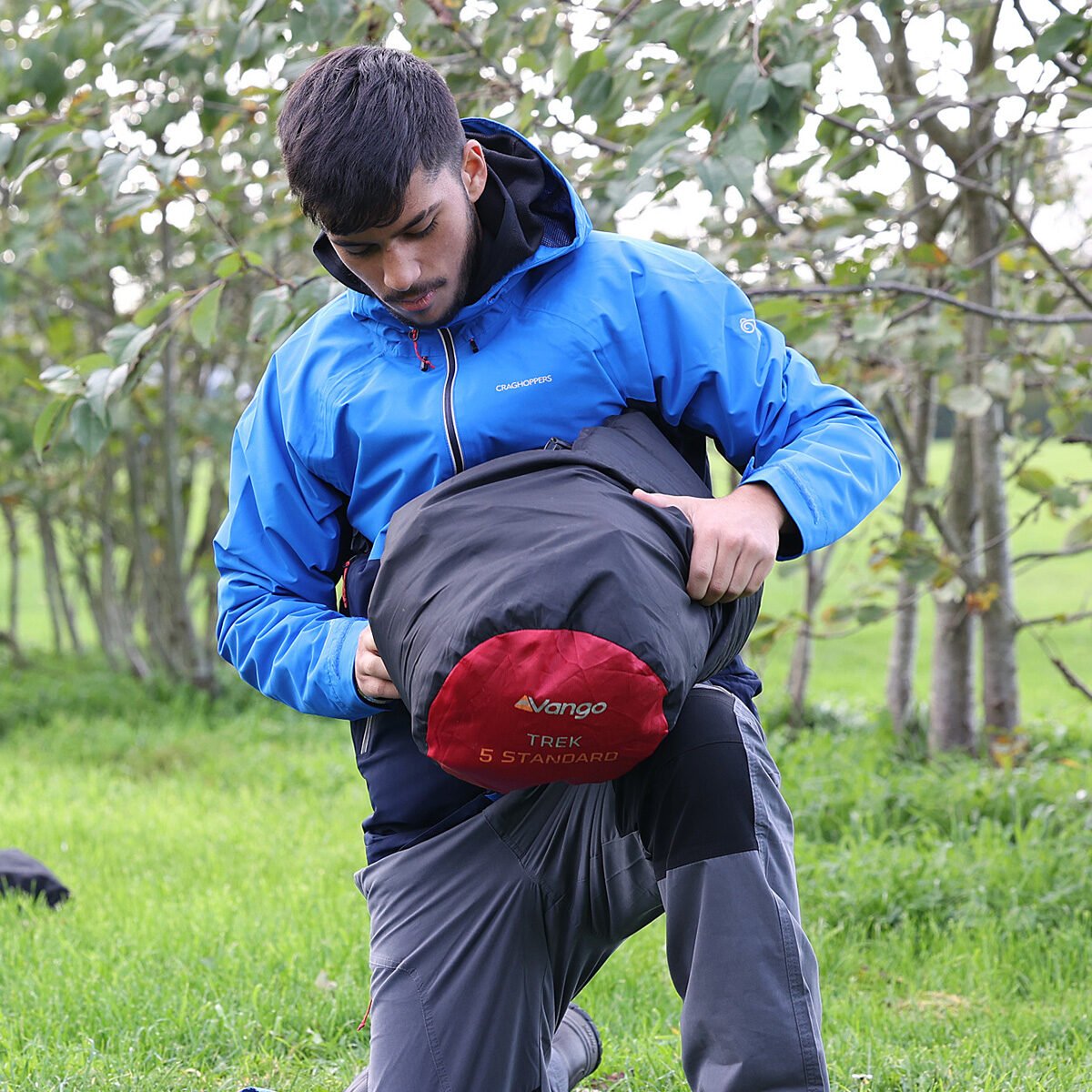 Young person packing a sleeping bag away.