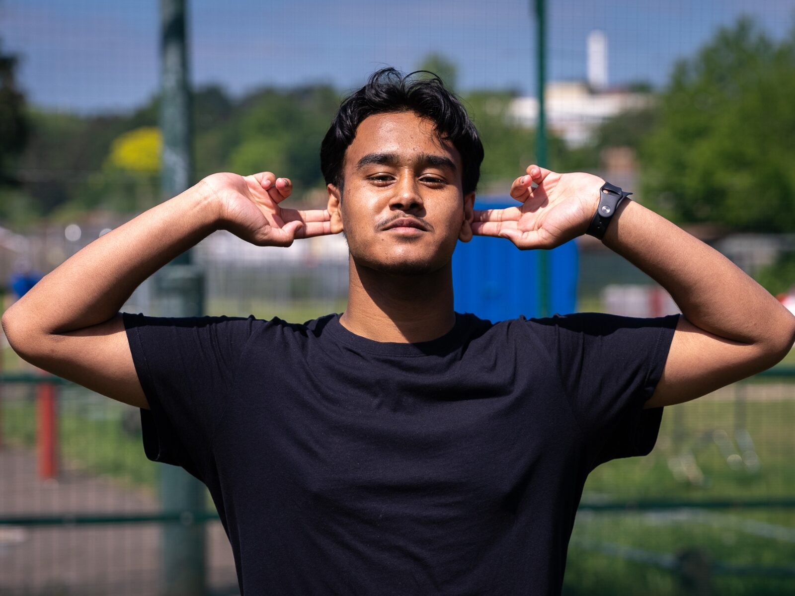 Young person is holding both hands up and cupping their ears.