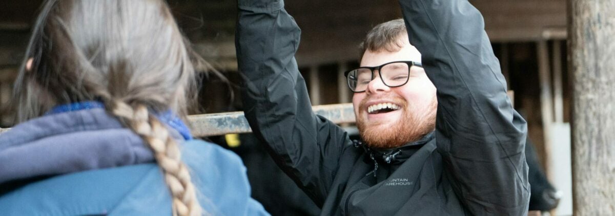A young person holding their arms up in the air celebrating and smiling.