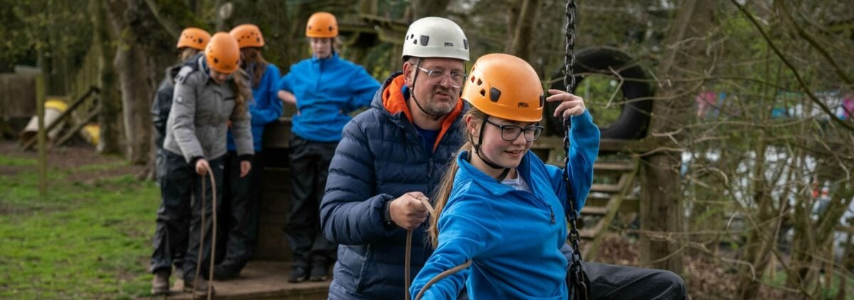 A D of E volunteer helps a participant through an obstacle course.