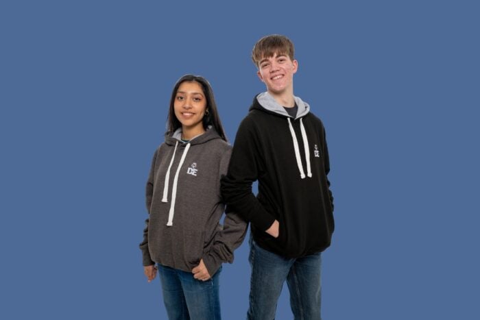 Two young people standing back to back, both wearing DofE Hoodies.